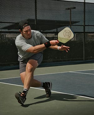 Pickleball Guides für Anfänger. Pickleball Spieler beim Schlag auf dem Court – Symbolbild