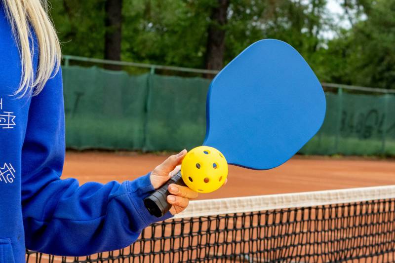 Pickleball spielen in Stuttgart – Schläger und Ball auf dem Court Pickleball in Stuttgart: Spielerin hält Pickleball-Schläger und Ball auf Outdoor-Court